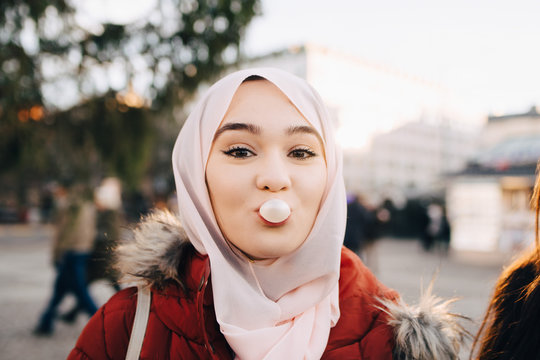 Portrait of young woman blowing bubble gum