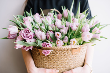 Young woman holding a wicker basket of fresh blossoming tulips