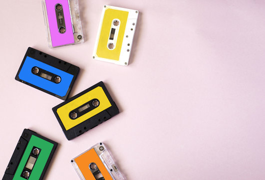 Retro cassette tape collection on pink background, top view, copy space.