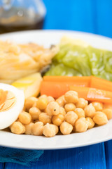 boiled cod fish with potato, carrot, cabbage , chick-pea and egg on white plate