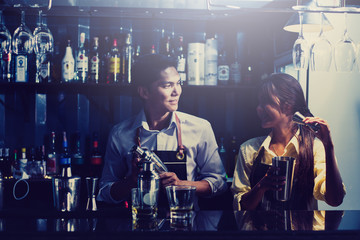 couple bartender shaking cocktails in counter at nightclub.