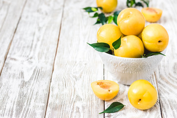 Ripe yellow plums on wooden board. Selective focus, space for text. 