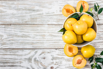 Fresh fruit, ripe yellow plums on wooden board. Top view, copy space.