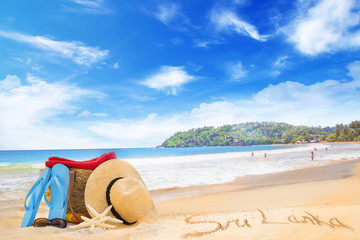 Fototapeta na wymiar Straw hat, sunglasses, slippers and a bag on the golden sand of Sri Lanka's beach