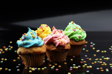 Tasty cupcakes on dark background. Birthday cupcake in rainbow colors.