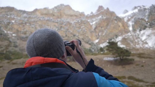 Man takes a picture on a camera in the mountains