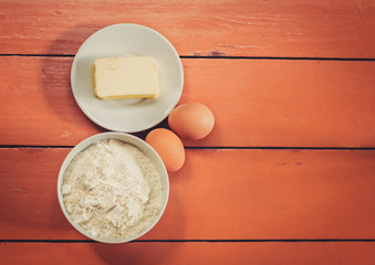 Flour, eggs and butter on rustic painted wooden background. Top view with copy space.