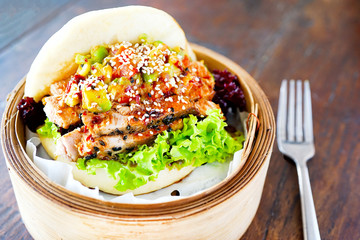Grilled tuna and guacamole bao. Female hand with chopsticks. Wooden table background in a restaurant. Teapot of green Chinese tea. Traditional Chinese and French cuisine. Top view with copy space