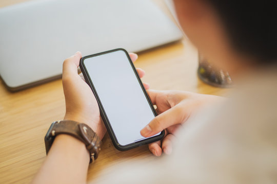 Man Holding A Phone With White Screen Over The Desk In The Office