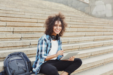 Happy young woman using digital tablet outdoors