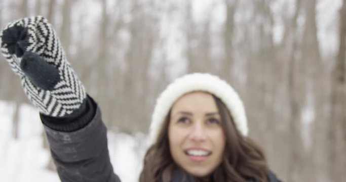 Beautiful woman outdoors in winter forest points with mitten up into trees
