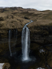 Aerial photograph of a waterfall dropping down a overgrown cliff at Seljalandsfoss, Iceland