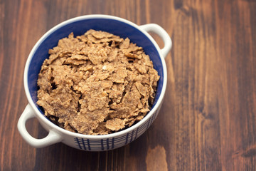 cereals in white blue bowl on brown background