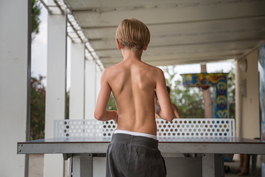 Rear View of Ten Year Boy Playing Table Tennis Shirtless in the Park