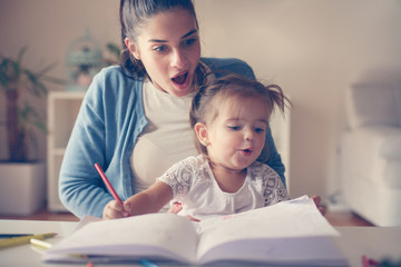 Fototapeta premium Shocked young mother at home watching her daughter how to draw.