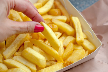 Woman hand takes potato fried chips in card box on paper takeaway