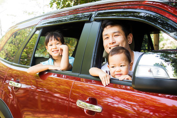 Asian family smiling in red car. Father and two daughter happiness emotion. Concept of vacation road trip.