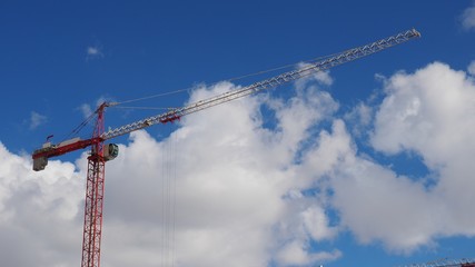Construction tower crane against blue sky and white clouds