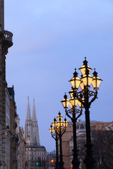 Ornate historical lamp posts outside Rathaus Vienna, or Vienna Town Hall in the evening.