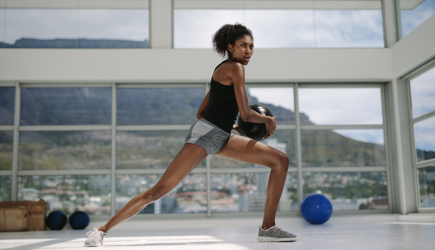 African girl doing stretching exercise with medicine ball