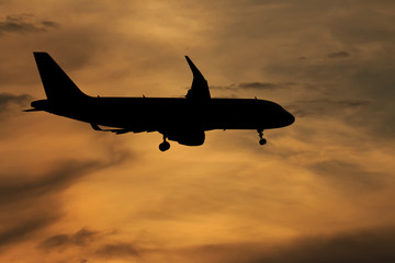 Silhouette passenger airplane flying away in to sky high altitude on sunset