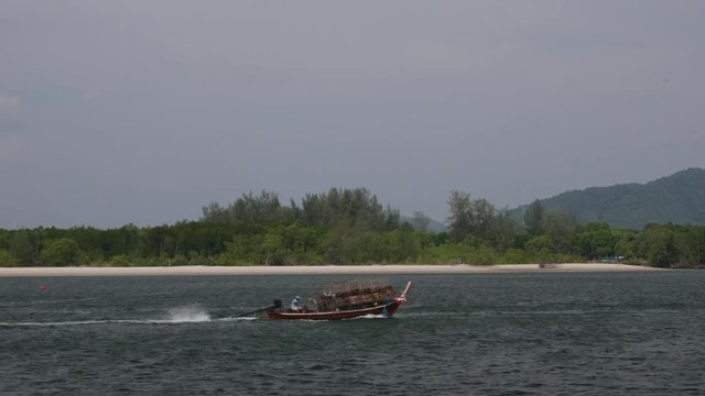Traditional thai wooden boat loaded with fish trap sail in the sea.