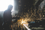 Man works with grinder cutting metal.