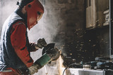 Man works with grinder cutting metal.