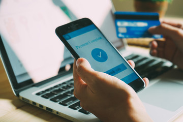 Hands using smartphone and laptop computer for online shopping at home