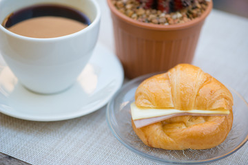 Ham and cheese croissant with coffee background