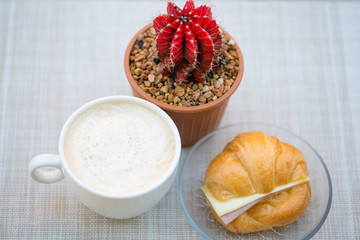 A cup of coffee with Ham and cheese croissant