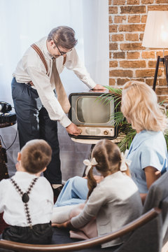 Mother With Two Kids Looking At Father Turning On Vintage Tv, 1950s Style