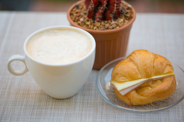 A cup of coffee with Ham and cheese croissant