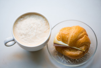A cup of coffee with Ham and cheese croissant