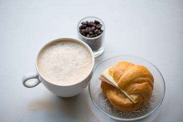 A cup of coffee with Ham and cheese croissant