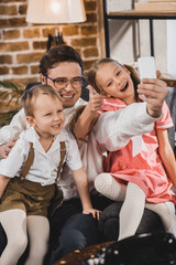 Fototapeta na wymiar happy 1950s style family taking selfie with smartphone at home