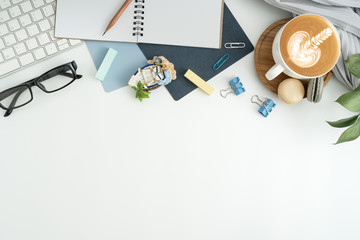 Styled stock photography white office desk table with blank notebook, keyboard, macaroon, supplies and coffee cup. Top view with copy space. Flat lay.