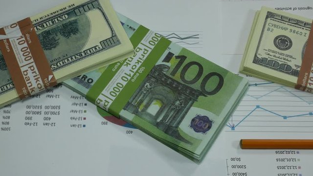Modern graphs of financial expenses and income on the table with dollars, euro and contract in the business center.