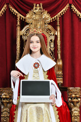 Beautiful teen girl holding laptop sitting in vintage armchair