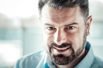 Obraz premium Positive thoughts. Attractive man feeling happiness while looking at you, having pause at work