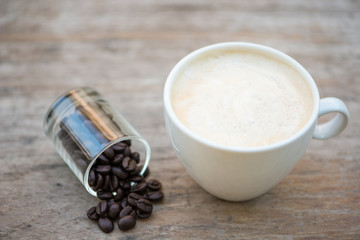 Acup of coffee and bean in glass on wood floor