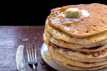 Pancakes with maple sauce on a dark table.