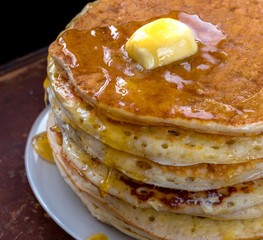 Pancakes with maple sauce on a dark table.