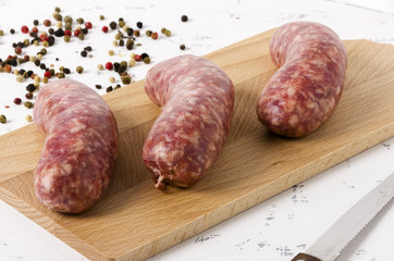 Three sausages on the chopping board on white background and peppercorn