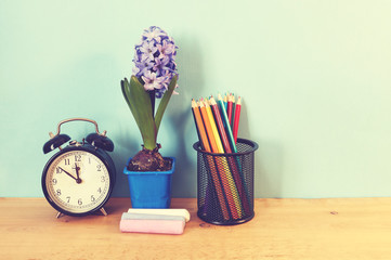 School supplies and flowers on wooden background