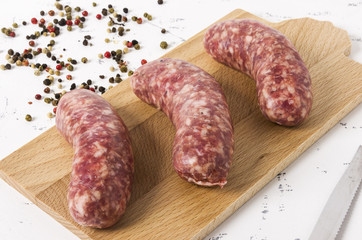 Three sausages on cutting board, on white background.