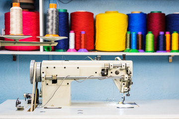 sewing machine overlock in tailor workshop on the background of a shelf with colorful threads