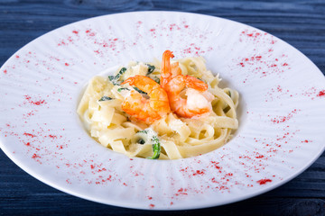 Fresh penne pasta with tomato sauce shrimp and oregano on a blue background
