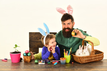 Father and child painting Easter eggs. Bunny ears concept. Child holding basket with painted eggs.