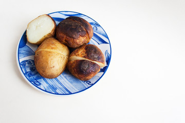 Baked potatoes in a skin on a porcelain plate. Candid, copy space.